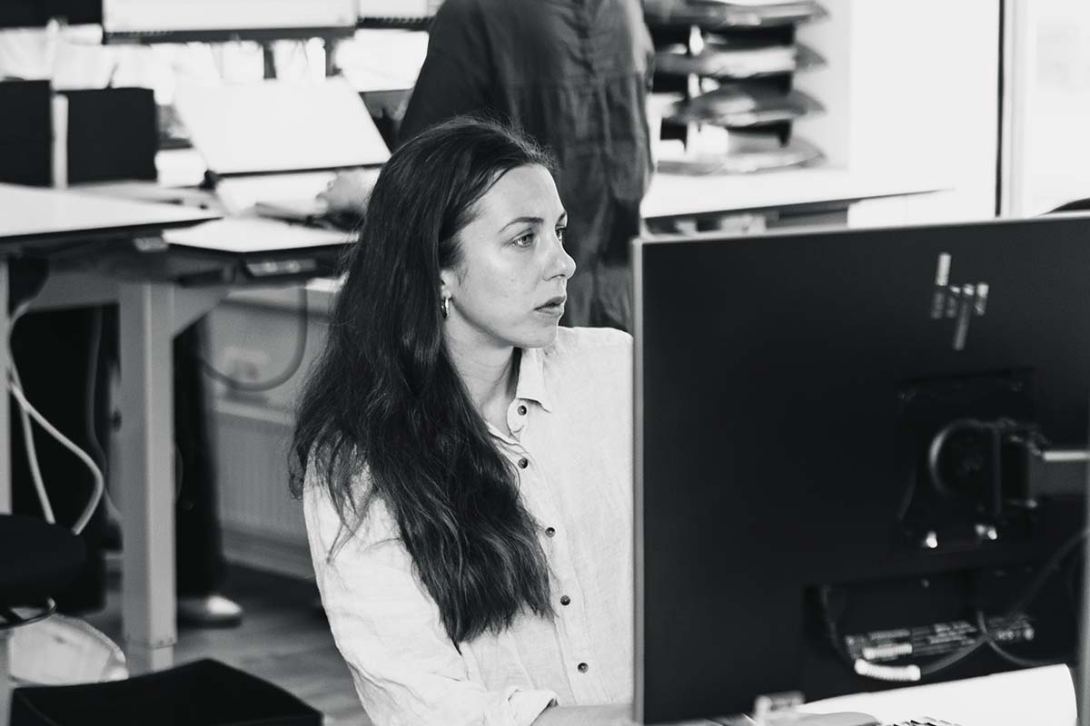 En ung kvinna sitter framför en dator på ett kontor